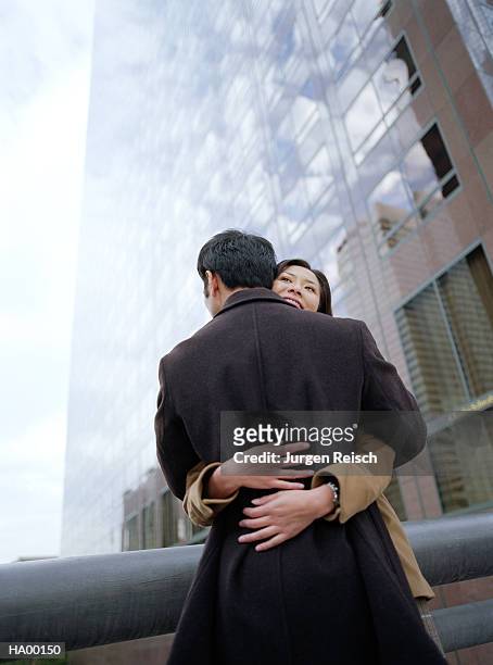 couple embracing by skyscraper - jurgen stockfoto's en -beelden