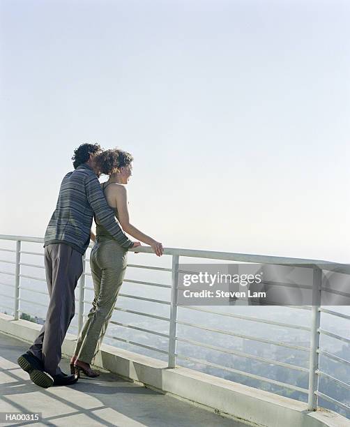 young couple leaning on railing looking out at view, rear view - lam stock pictures, royalty-free photos & images