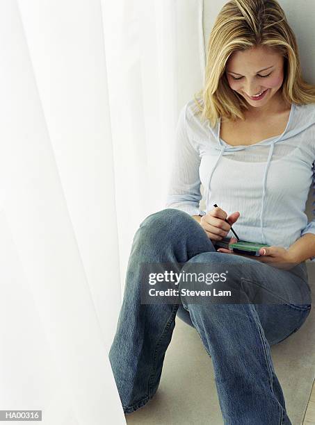 young woman sitting on floor, looking at electronic organizer - lam stock pictures, royalty-free photos & images