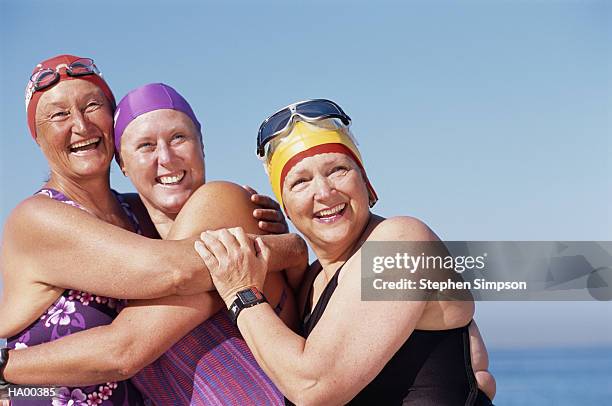 three mature women at beach, embracing, portrait - swimming cap stock pictures, royalty-free photos & images