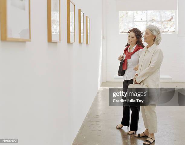 mature woman and granddaughter looking at gallery exhibit - gallery 2 stock pictures, royalty-free photos & images