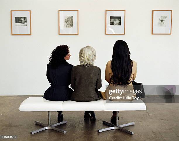 three generations of women looking at exhibit in art gallery - museum stockfoto's en -beelden