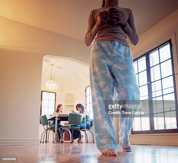 young woman in living room holding coffee cup, friends in background - tony garcia stock-fotos und bilder