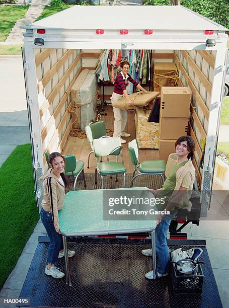 three young adults moving furniture from back of moving truck - tony garcia stock-fotos und bilder