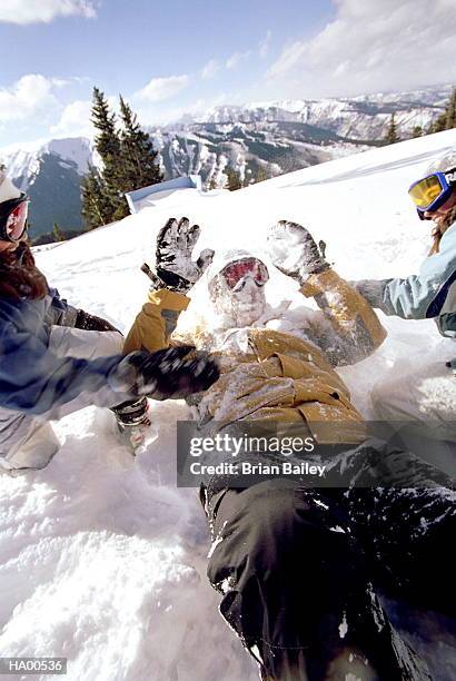 two girls (12-14) throwing snow at father, close-up - brian stock-fotos und bilder