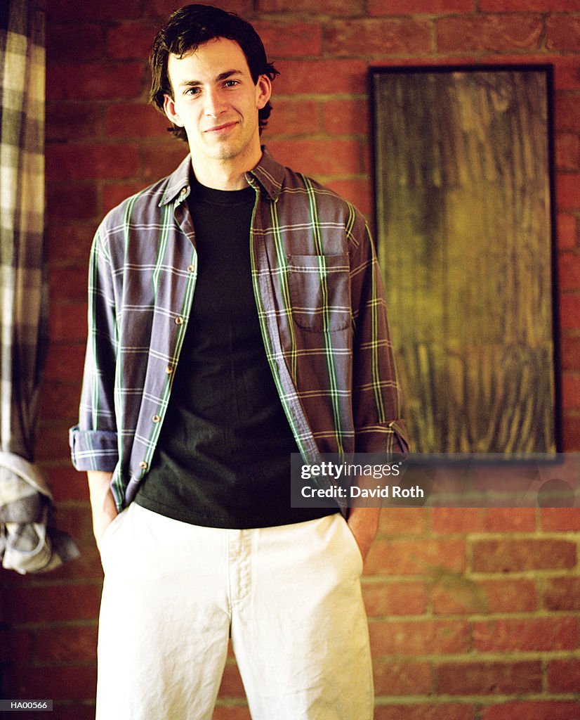 Young man in plaid shirt standing in living room