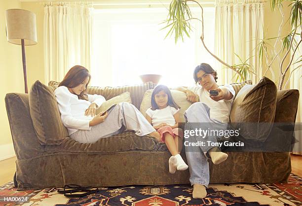 mother and father sitting on couch with daughter (4-6) - garcia stock-fotos und bilder