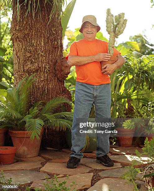 mature man standing outside, holding potted cactus plant - garcia stockfoto's en -beelden