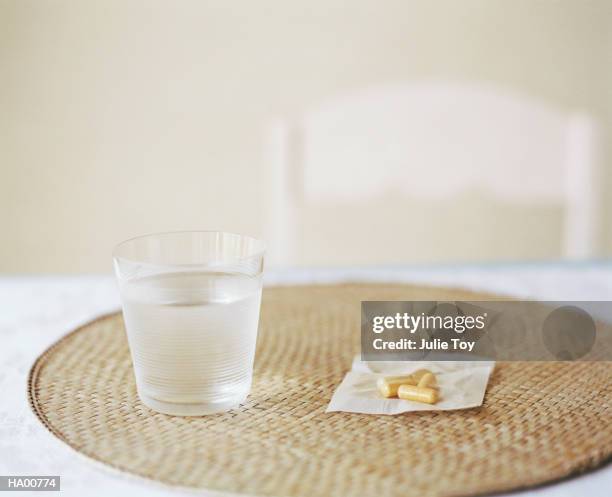 glass of water and pills on placemat - apothecary table stock pictures, royalty-free photos & images
