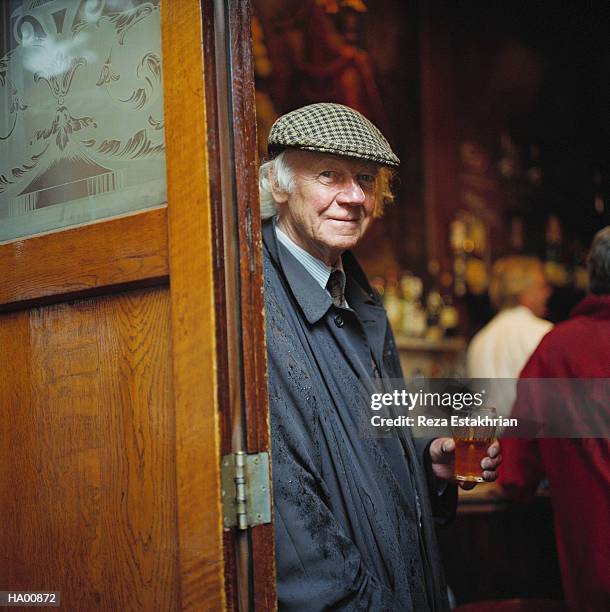 mature man wearing hat, holding glass of beer, portrait - british pub stock pictures, royalty-free photos & images