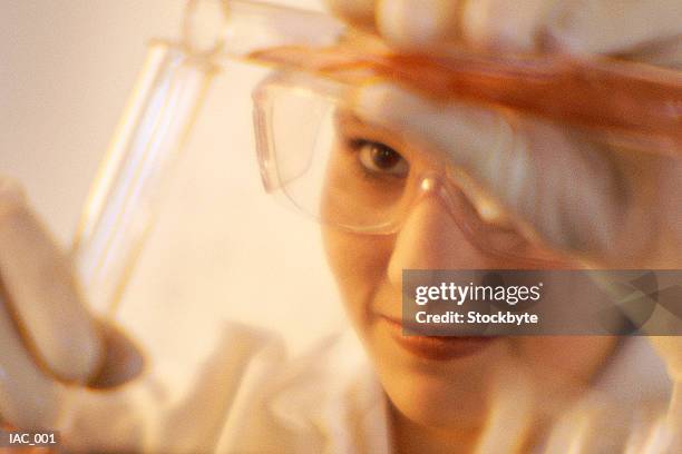 woman pouring liquid from one test tube to another - exame de drogas - fotografias e filmes do acervo