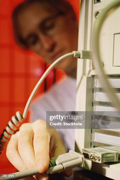 man connecting cable to back of computer - datorport bildbanksfoton och bilder