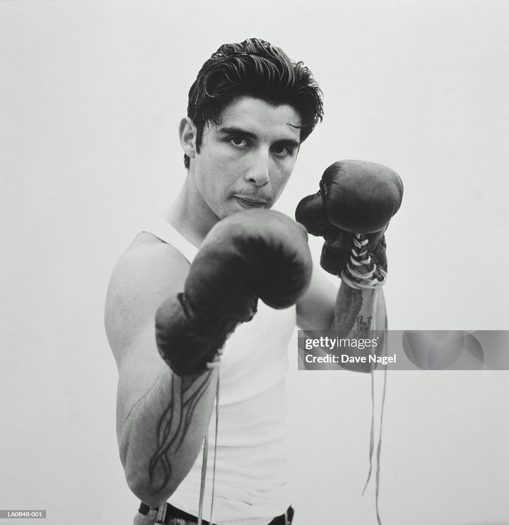 Young man wearing boxing gloves, portrait (B&W)