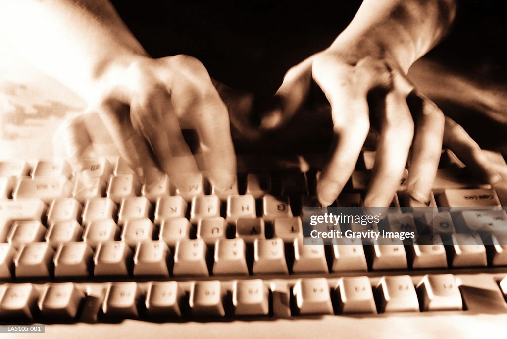 Hands using computer keyboard, close-up (blurred motion,toned B&W)