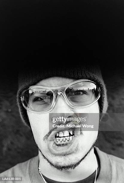 young man with gold teeth spelling jems, grimacing, portrait (b&w) - capped tooth stock-fotos und bilder