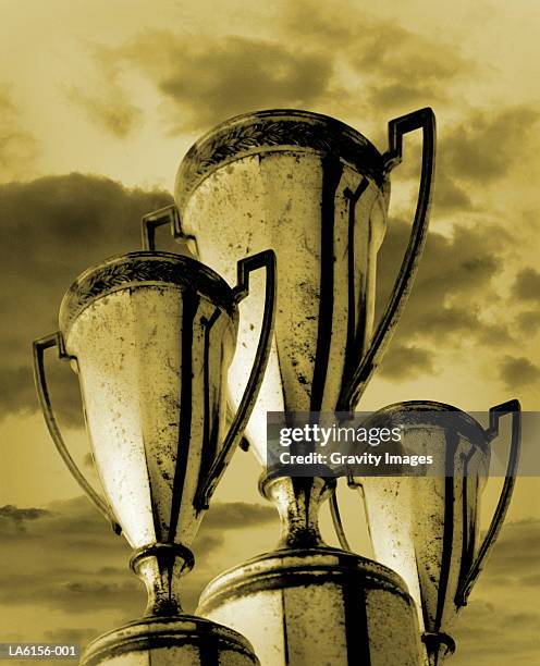 three trophies against cloudy sky, low angle view (digital composite) - awards day 3 stock pictures, royalty-free photos & images