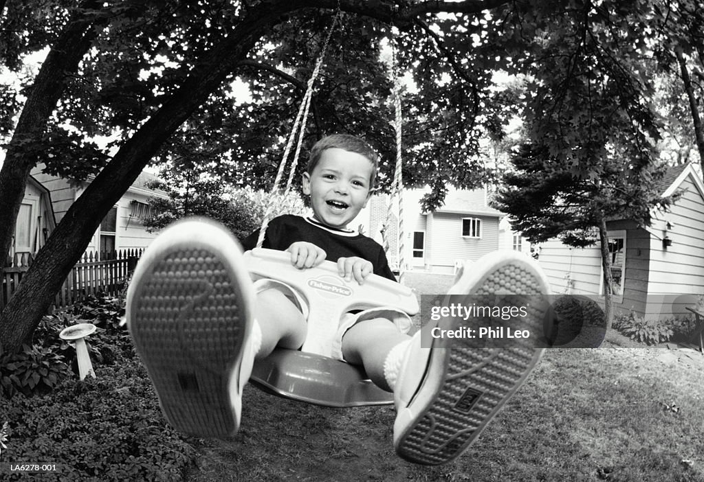 Boy (2-4) on swing in garden (wide angle, B&W)