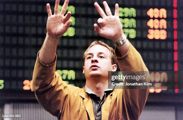 stock trader gesturing in front of trading board, close-up - börsensaal stock-fotos und bilder