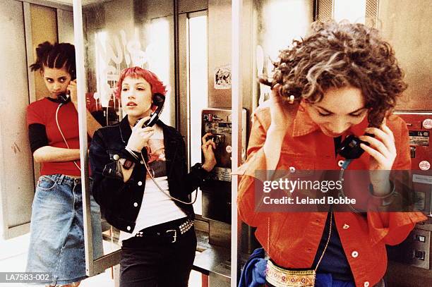three teenage girls (15-17) using public telephones (cross-processed) - pay phone stock pictures, royalty-free photos & images