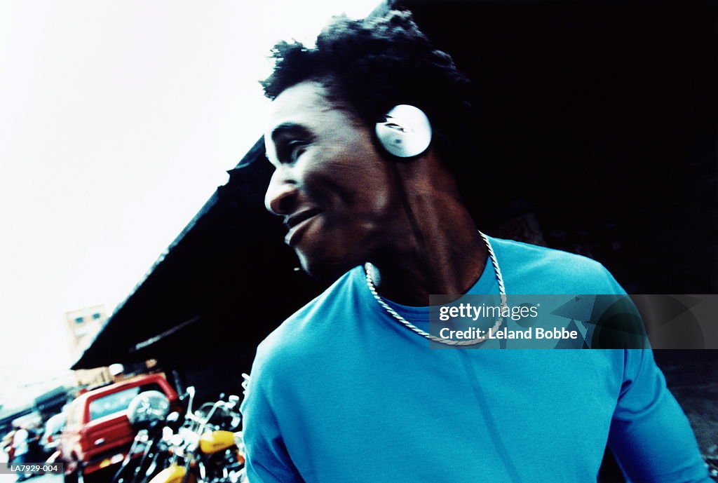 Young man wearing headphones, turning head, smiling (blurred)