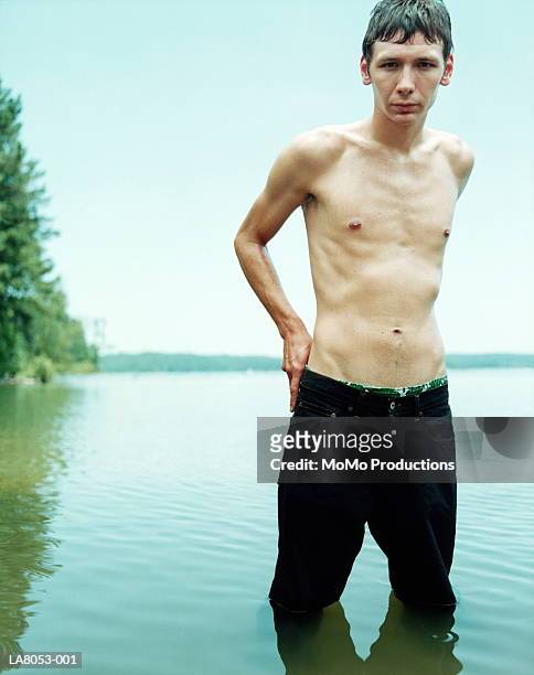 young man standing in water, wearing trousers, portrait - slim stock pictures, royalty-free photos & images