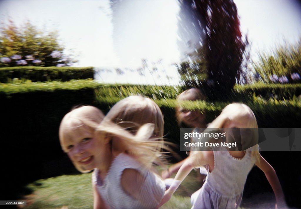 Twin girls (5-7) running outdoors, portrait (multiple exposure)
