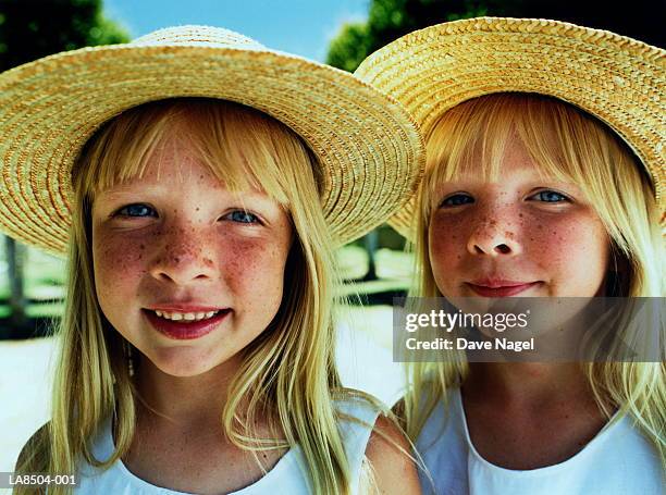 twin girls (5-7) wearing straw hats, close-up, portrait - twin stock-fotos und bilder