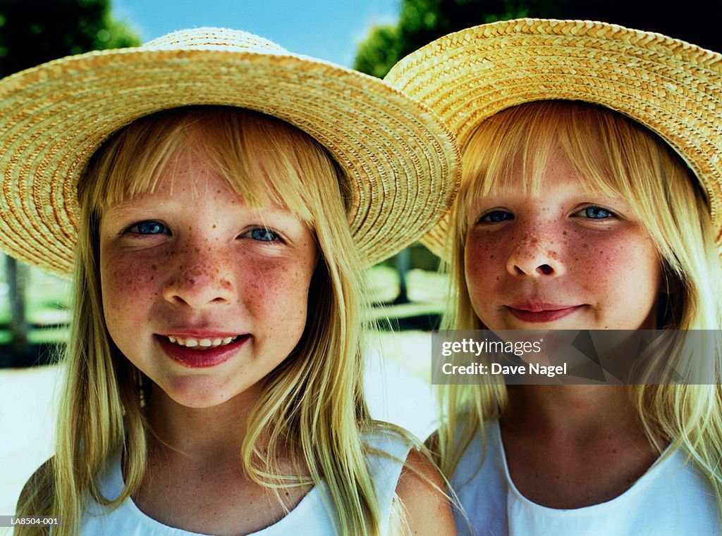 Twin girls (5-7) wearing straw hats, close-up, portrait