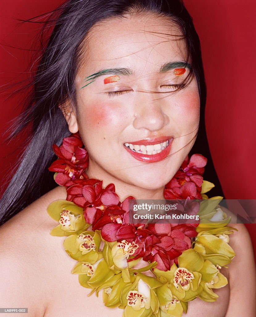 Young woman wearing flower lei, eyes closed, portrait