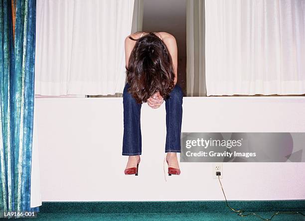 woman sitting on hotel room windowsill, head bowed - high heels photos fotografías e imágenes de stock