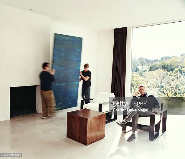 three men in living room, focus on man using mobile phone - removal men imagens e fotografias de stock