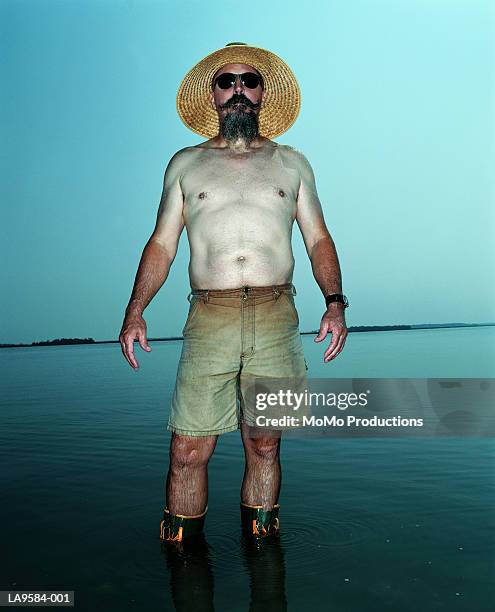 mature man standing in water, portrait - raya del bronceado fotografías e imágenes de stock