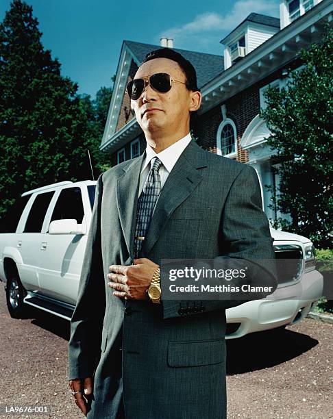 suited man with car outside house, portrait - young-urban-professional-person stock-fotos und bilder