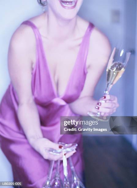 woman leaning forward with champagne glasses in hand, close-up - abendgarderobe stock-fotos und bilder