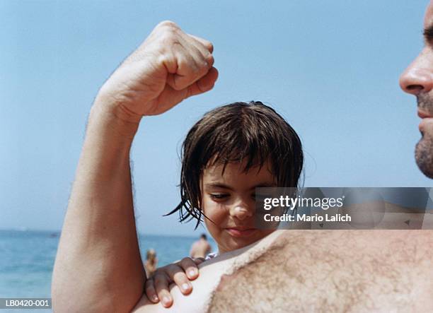 girl (5-7) feeling father's muscles on beach, close-up - female hairy chest stock-fotos und bilder