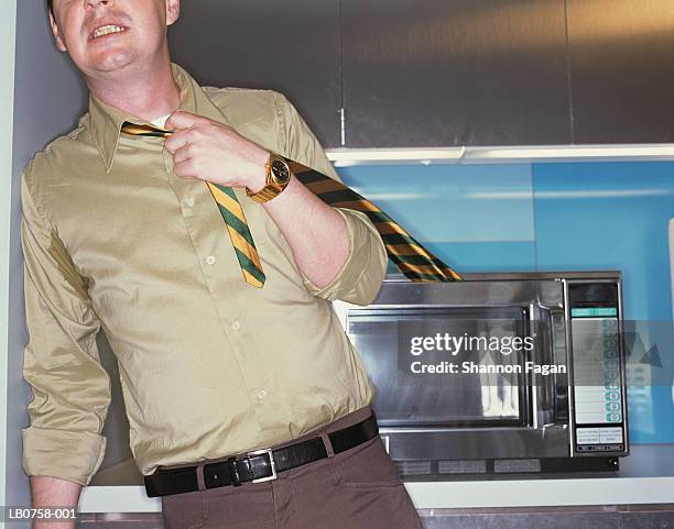 man with tie stuck in microwave - choking food stock-fotos und bilder