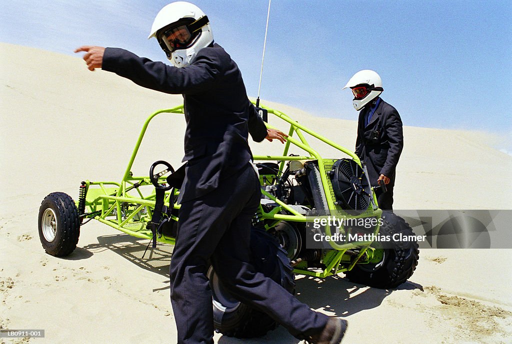 Two businessmen standing by dune buggy, profile