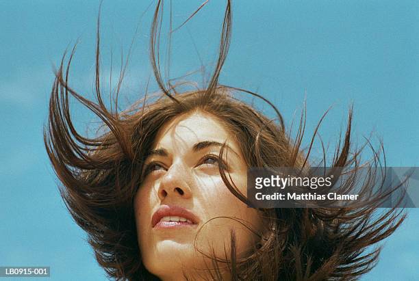 young woman standing outdoors, hair blowing, close-up - hoffnung stock-fotos und bilder
