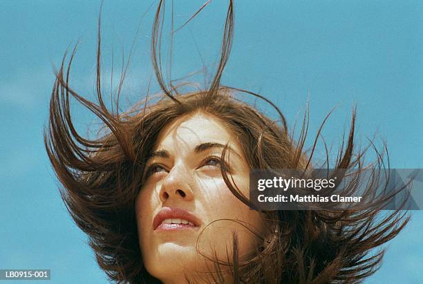 young woman standing outdoors, hair blowing, close-up - sensory perception stockfoto's en -beelden