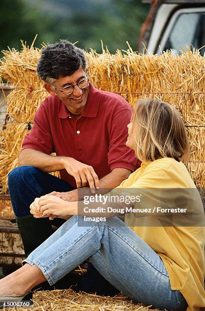 couple sitting on a bale of hay - hay fotografías e imágenes de stock