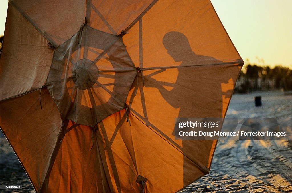 Silhouette of Man Opening a Beach Umbrella