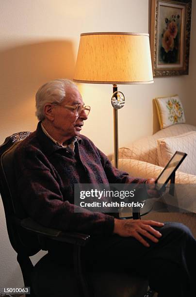 elderly man looking at photograph - widower stock pictures, royalty-free photos & images