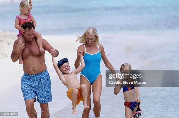 family on the beach - ankle deep in water stock pictures, royalty-free photos & images