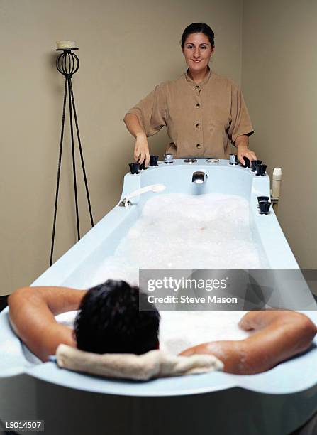 man in hot tub and spa attendant - balneotherapy stock pictures, royalty-free photos & images