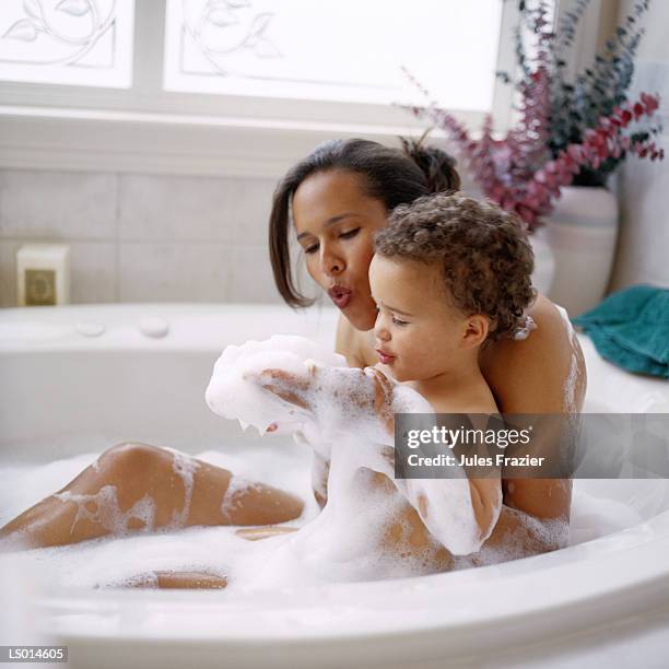 mother and son taking a bubble bath - kid bath mother stock-fotos und bilder