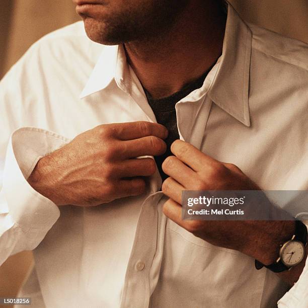 man buttoning shirt - curtis stockfoto's en -beelden