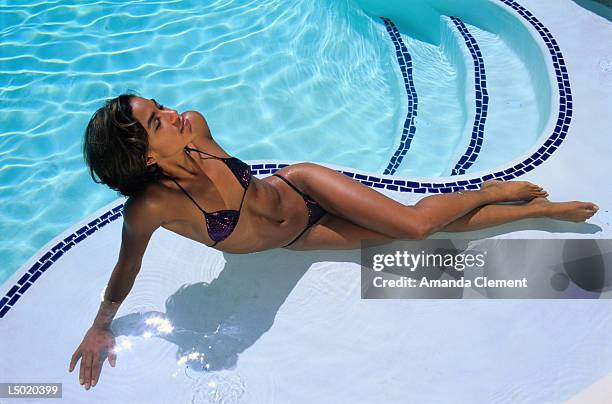 young woman sunbathing by swimming pool - amanda and amanda fotografías e imágenes de stock