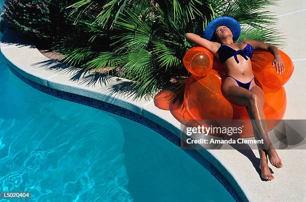 woman reclining by swimming pool - bubble chair stock-fotos und bilder