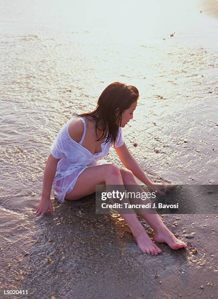 young woman sitting on beach - bavosi ストックフォトと画像