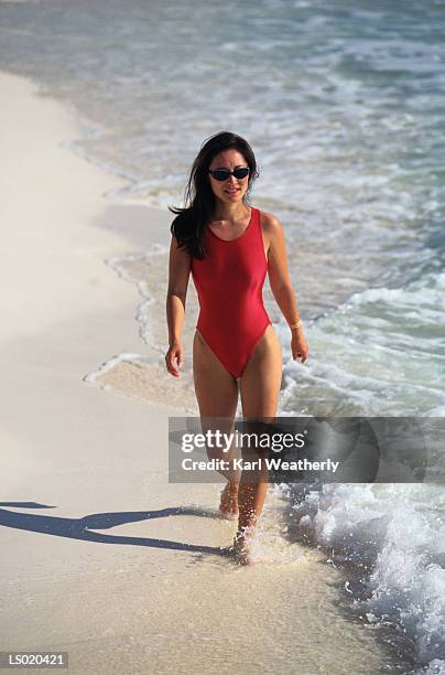woman walking on beach - swimming costume stock pictures, royalty-free photos & images